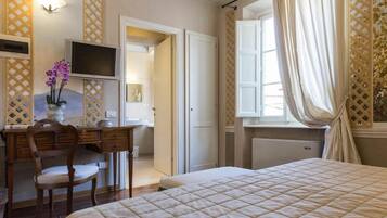 Una camera da letto con un letto, una scrivania con una sedia, una televisione e una finestra con tende.