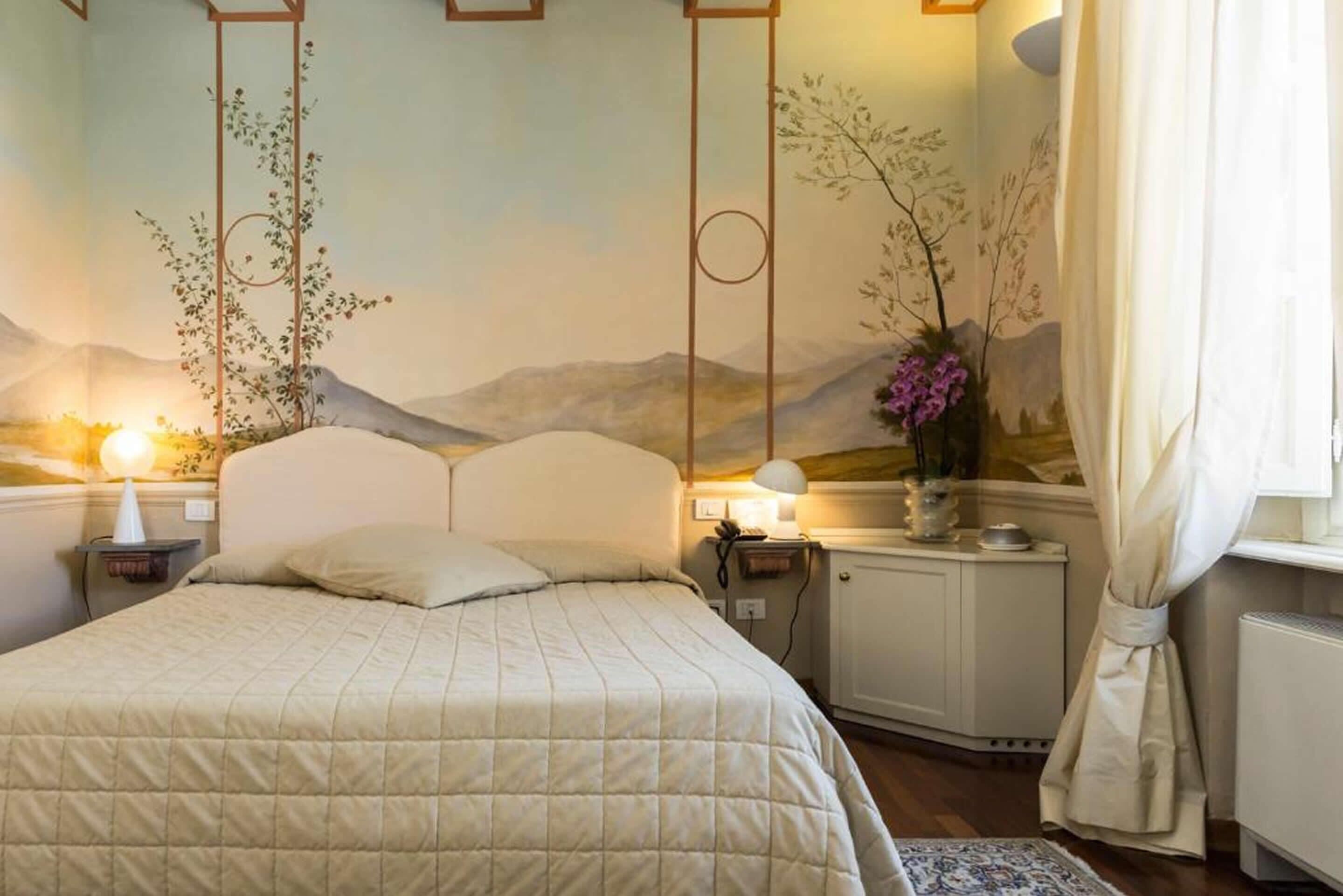 A bedroom with a bed, nightstands, a cabinet, and a window with curtains.