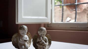 Due figurine di angeli su un tavolo vicino a una finestra con vista su un giardino.