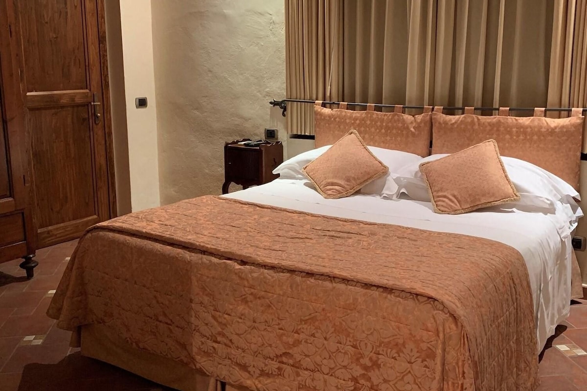 A bedroom with a large bed, a wooden wardrobe, and a curtain.