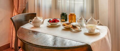 A table set for tea with teapots, cups, a bowl of berries, and a jar of honey.