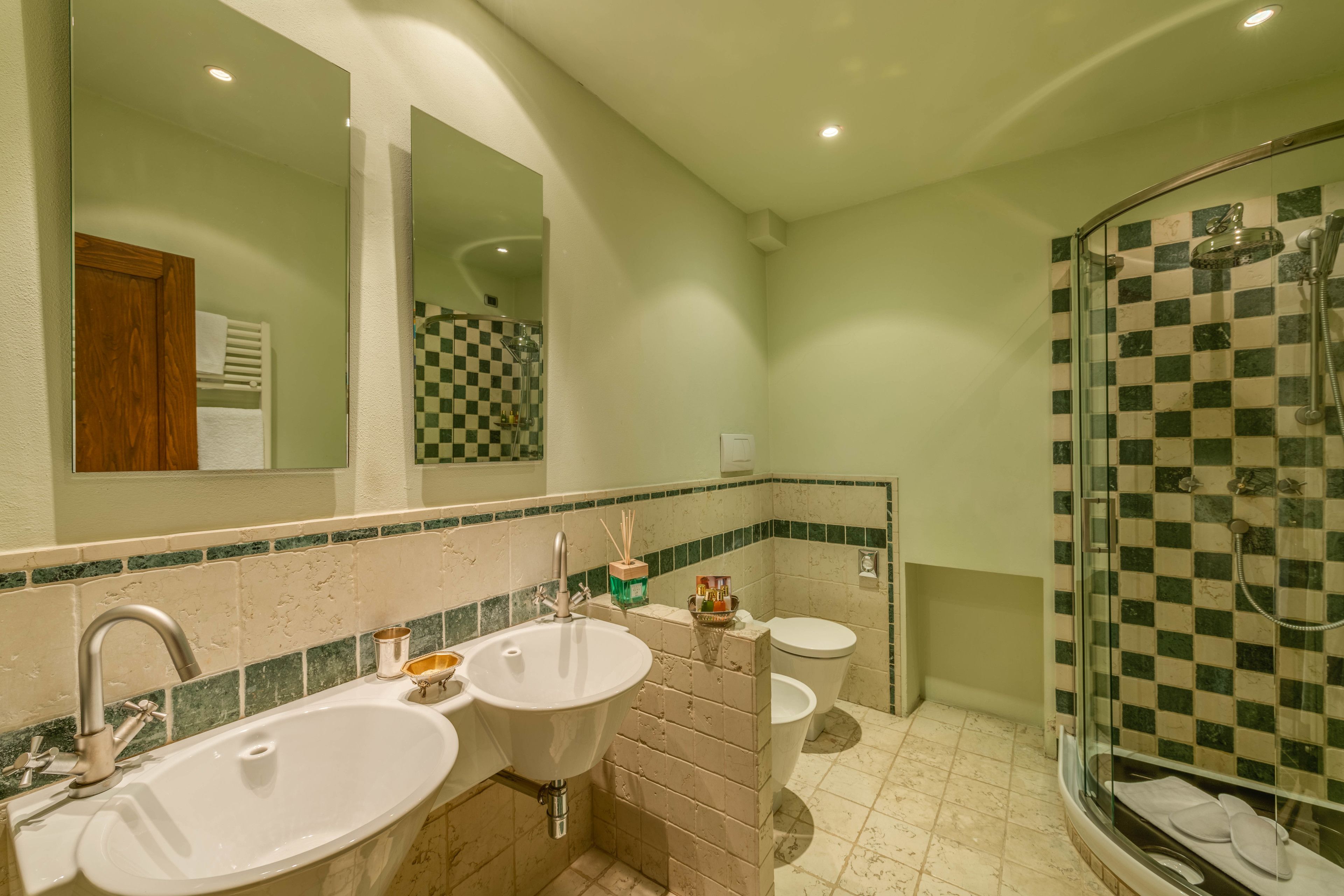 A bathroom with two sinks, a toilet, and a glass-enclosed shower area.