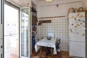A compact kitchen with a dining table, chairs, a refrigerator, and a tiled backsplash. - Abruzzese (Rome)