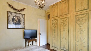 Une chambre à coucher comprenant un lit, un téléviseur posé sur un meuble en bois, une porte et une armoire ornée de panneaux décoratifs.