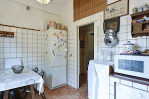 A compact kitchen with a white refrigerator, a microwave, and a dining table set for four. - Abruzzese (Rome)