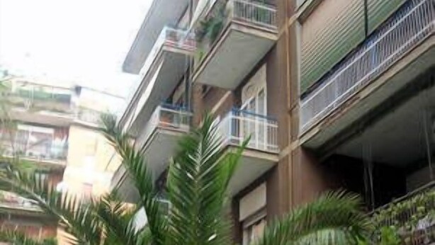 Un immeuble à plusieurs étages doté de balcons, dont certains sont ornés de plantes.
