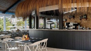 An outdoor bar area with a thatched roof, seating arrangements, and a counter with various bottles and glasses. - Prinsotel La Dorada (Muro)