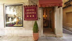 Ein Gebäude mit einem Schild, auf dem „Hotel Lisboa“ steht, und einem Blumentopf im Vorraum.