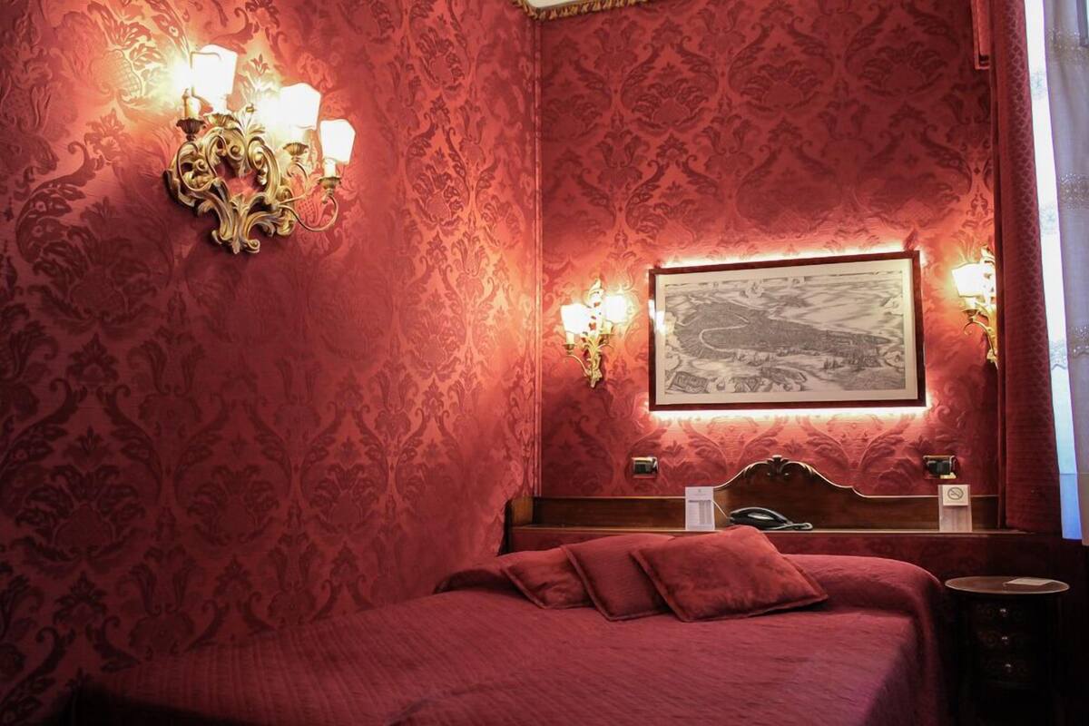 Une chambre comprenant un lit, une tête de lit, un tableau accroché au mur et deux appliques murales.