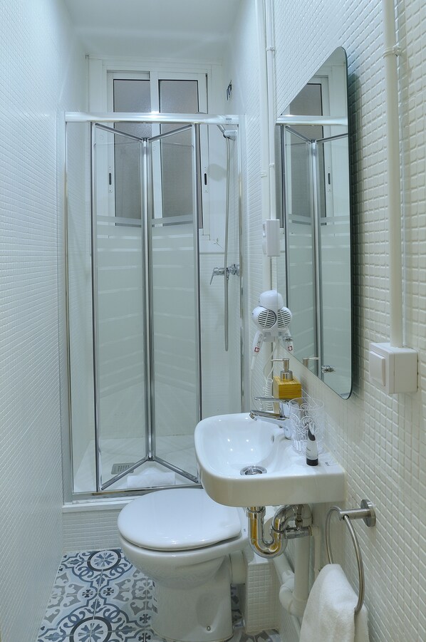 A compact bathroom with a glass shower enclosure, a white sink, and a toilet.
