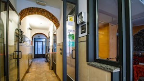 A hotel corridor with a herringbone floor, a stone archway, and a view of a dining area with a red tablecloth. - In Riva al Lago (Como)