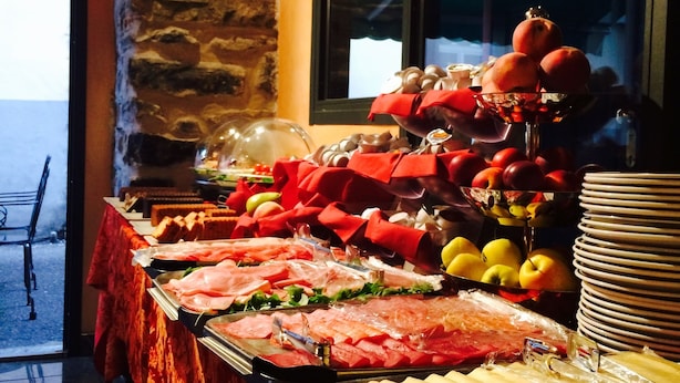 A buffet with various food items and a stack of plates. - In Riva al Lago (Como)
