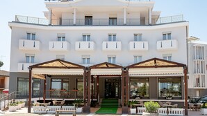 A hotel with a modern facade, balconies, and a covered entrance area with seating. - Hotel Milan (Rosolina)