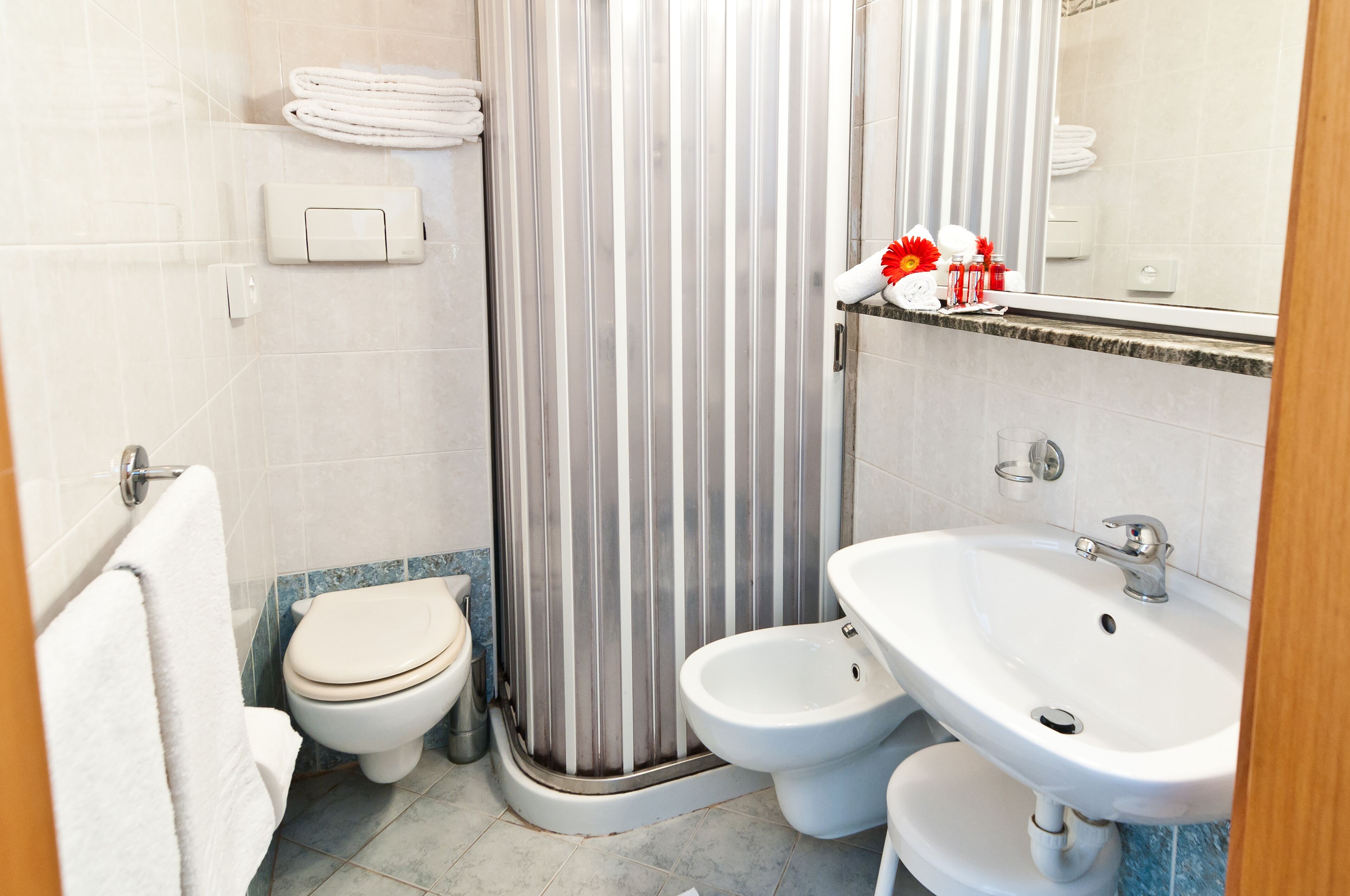 Une salle de bain équipée de toilettes, d’un bidet, d’un rideau de douche, d’un lavabo et d’un porte-serviettes.