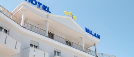 A hotel with a modern design, featuring balconies and a clear sky.