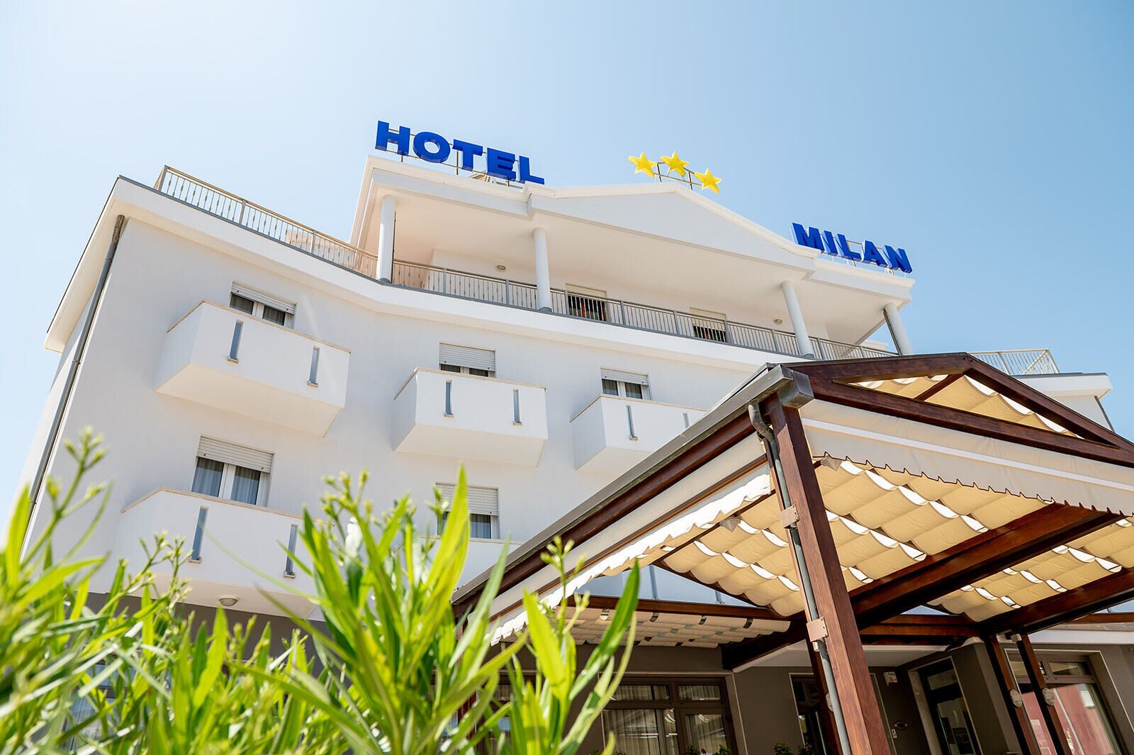 A hotel building with a modern design, featuring balconies and a clear sky.