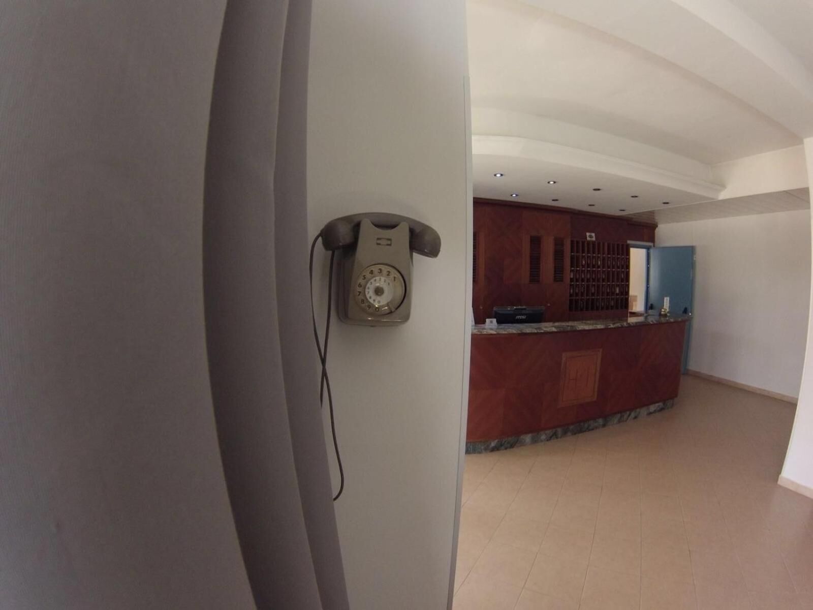 Un área de recepción con teléfono, mostrador y pared de paneles de madera.