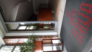 Interior de un hotel con varios niveles, una escalera visible, una zona de estar y una habitación con cama.