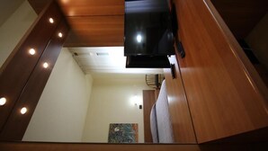 Un espacio habitable compacto con un televisor montado en un panel de madera, una zona de estar con cojines y un cuadro en la pared.