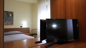 Una habitación de hotel con un escritorio de madera, televisor, cama y una silla.