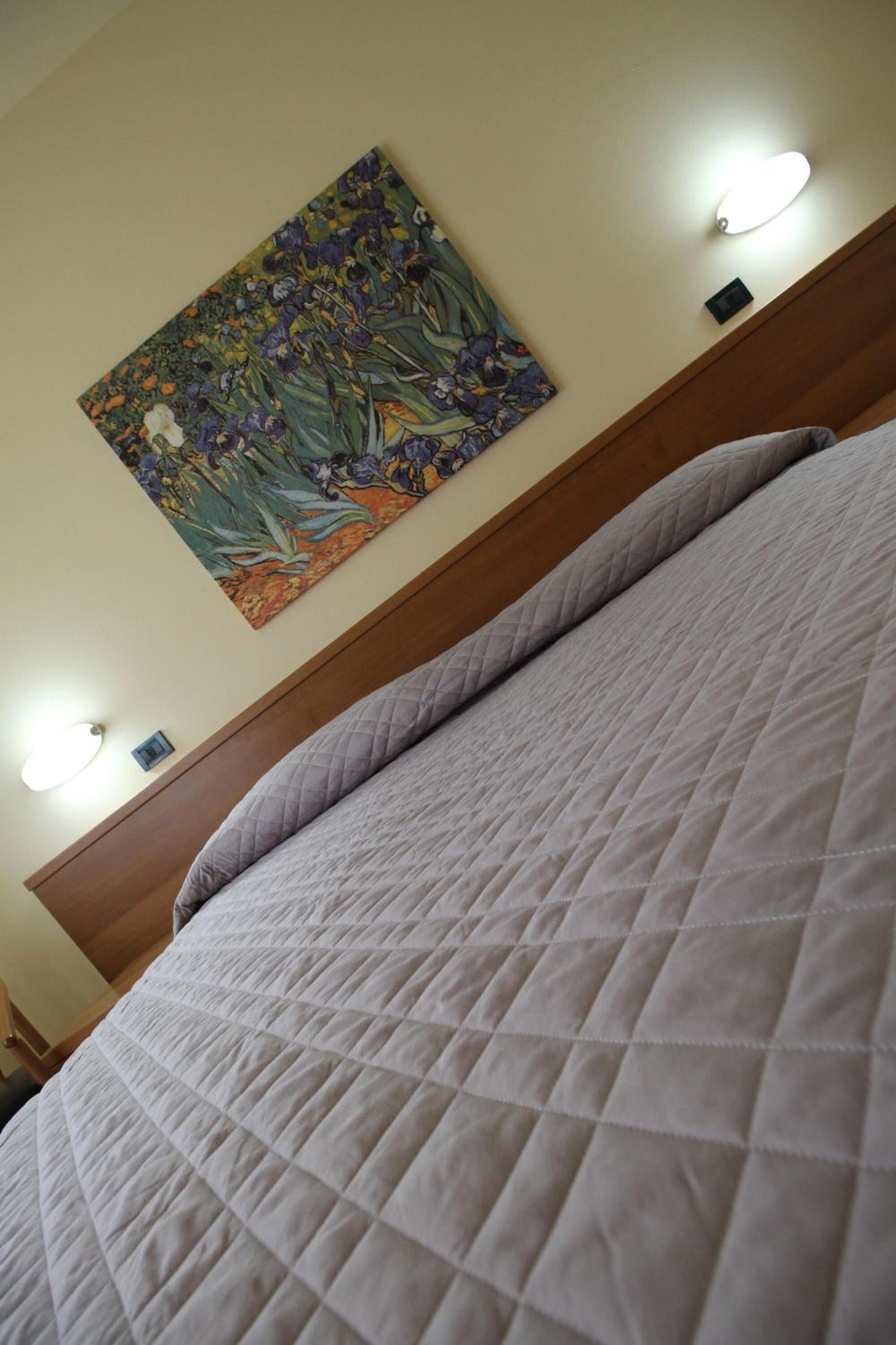 Ein Bett mit gesteppter Bettdecke und einem Blumengemälde an der Wand.