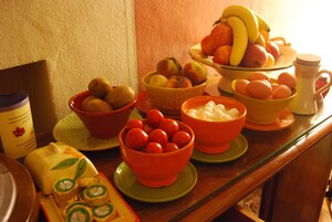 Un tavolo con diverse ciotole piene di frutta e verdura, una brocca e un pacchetto di snack.