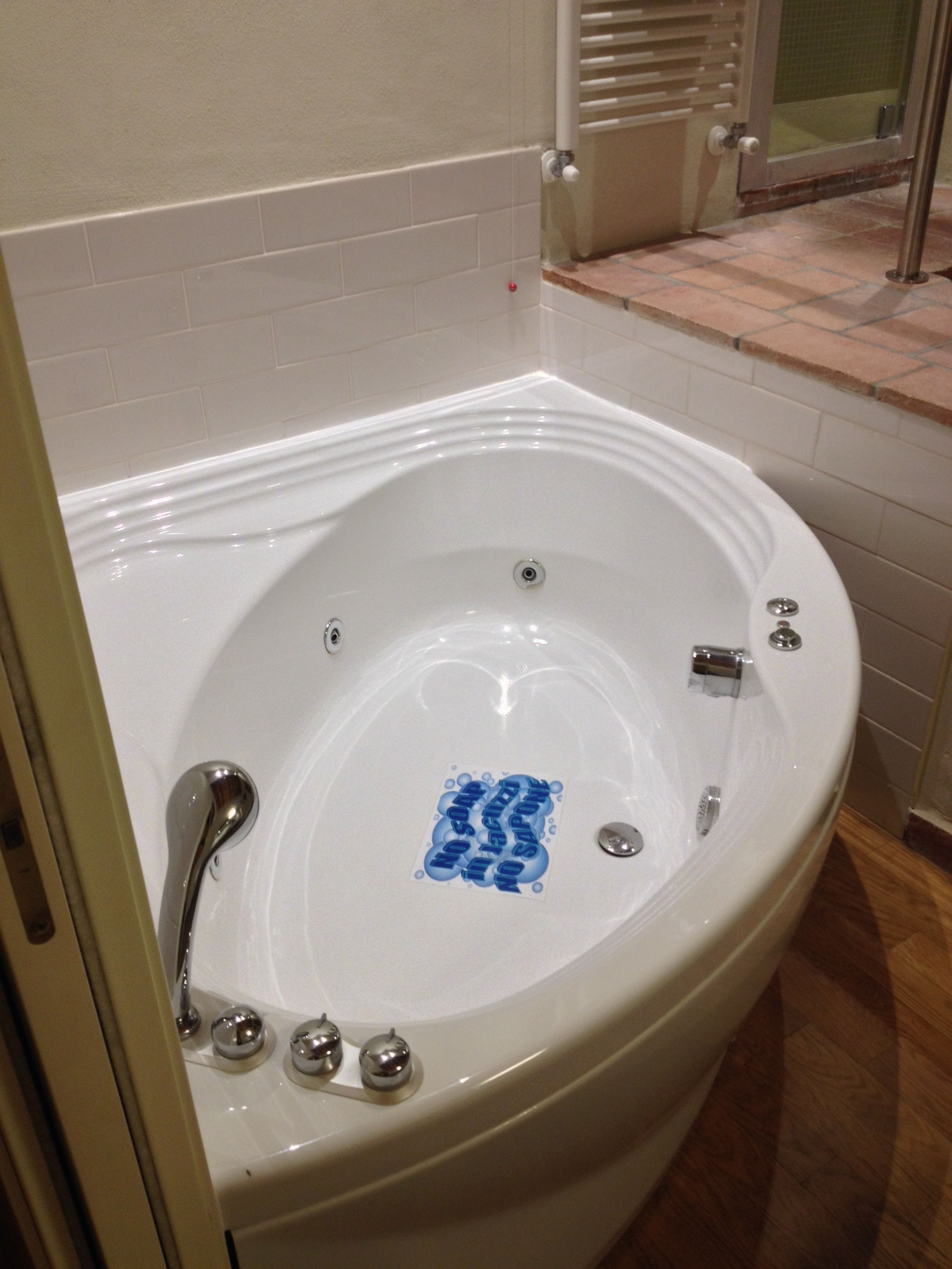 A white bathtub with a blue sticker, a showerhead, and a towel rack.