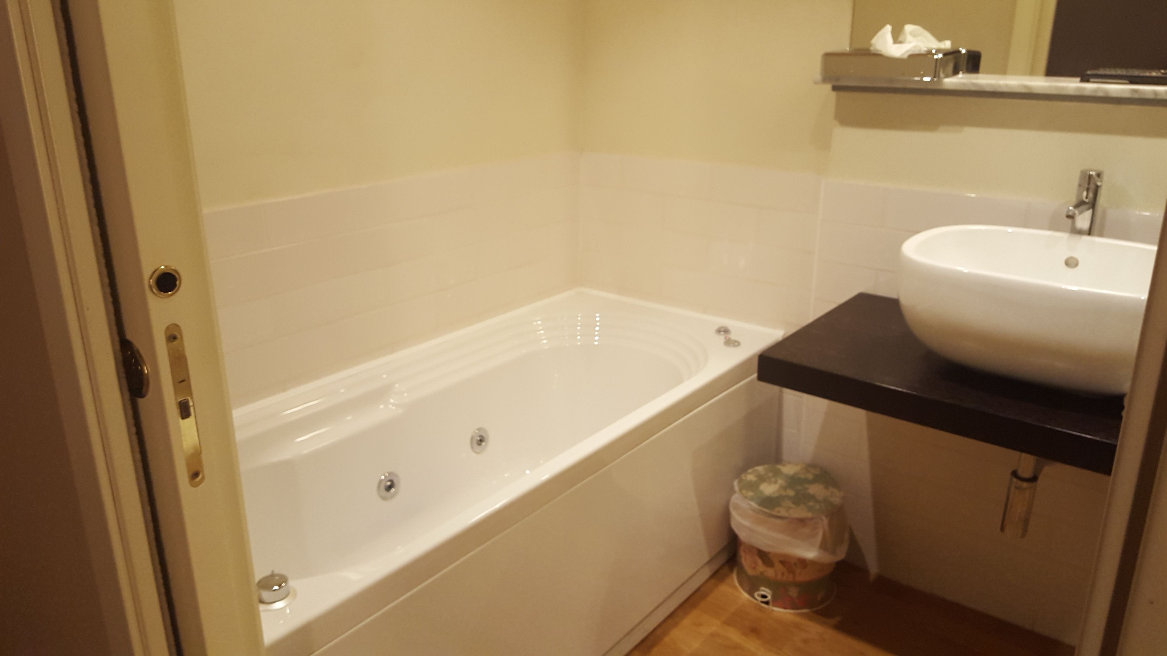 Une salle de bain avec une baignoire, un lavabo et une poubelle.