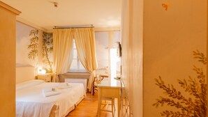 Ein Hotelzimmer mit zwei Betten, einem Schreibtisch und einem Fenster mit Vorhängen.
