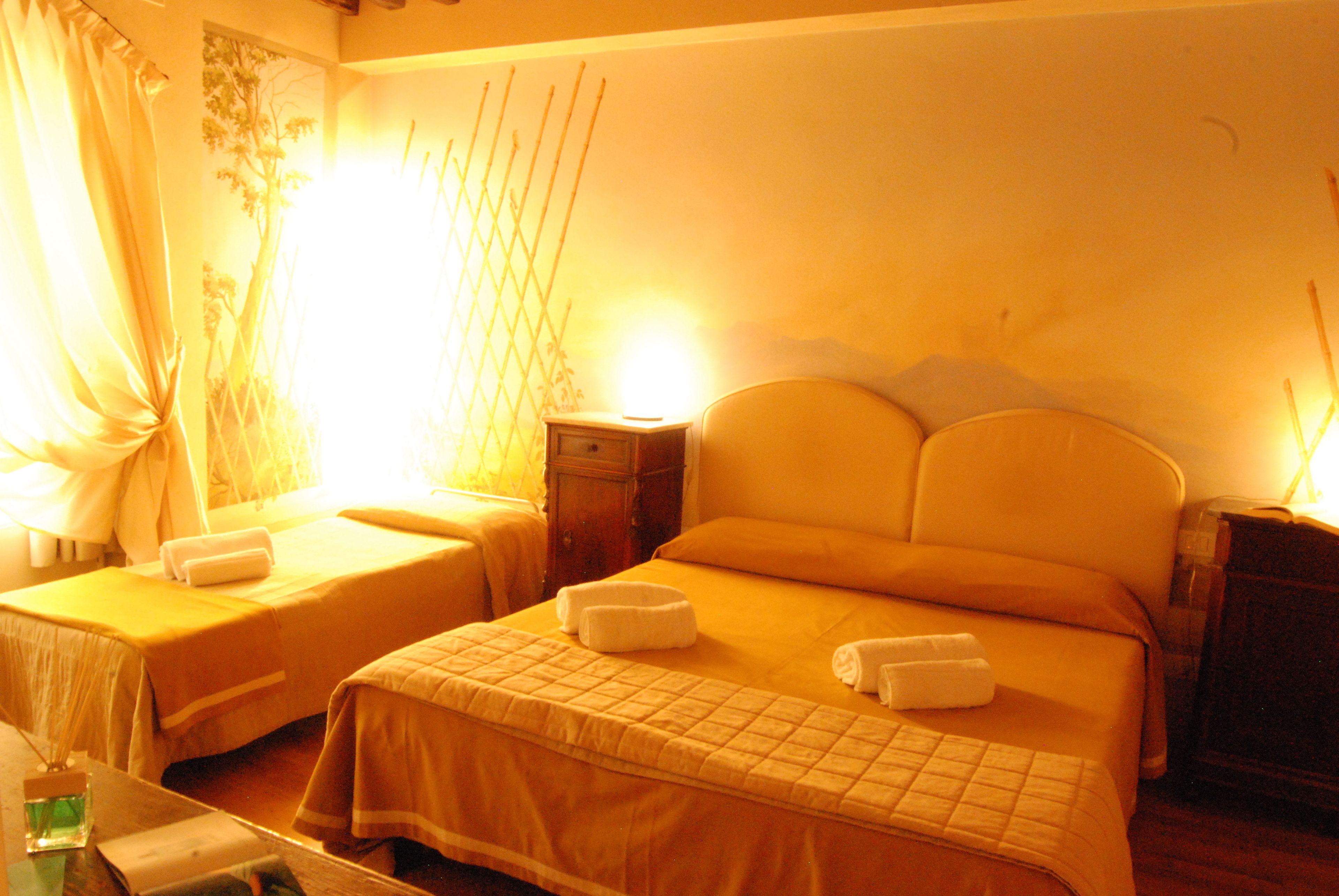 Une chambre d’hôtel avec deux lits simples, chacun étant équipé d’un oreiller et d’une serviette. On y trouve une petite table avec un verre d’eau et un livre.