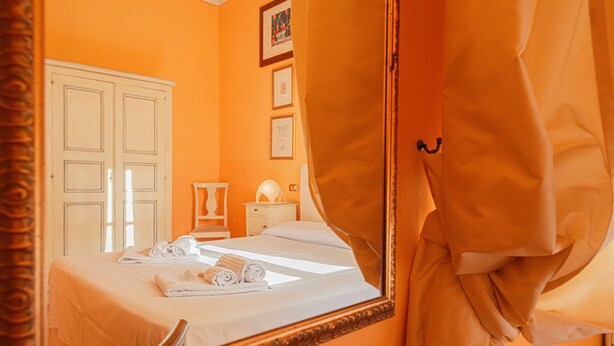 Una habitación de hotel con cama, mesita de noche, espejo y armario.