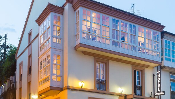 Un hotel con fachada clásica, múltiples ventanas y un letrero que indica que se encuentra en Herradura.