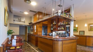 Una zona de bar con mostrador de madera, taburetes y una máquina de café.