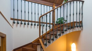 Una escalera de madera con barandilla curva y una lámpara en la pared.