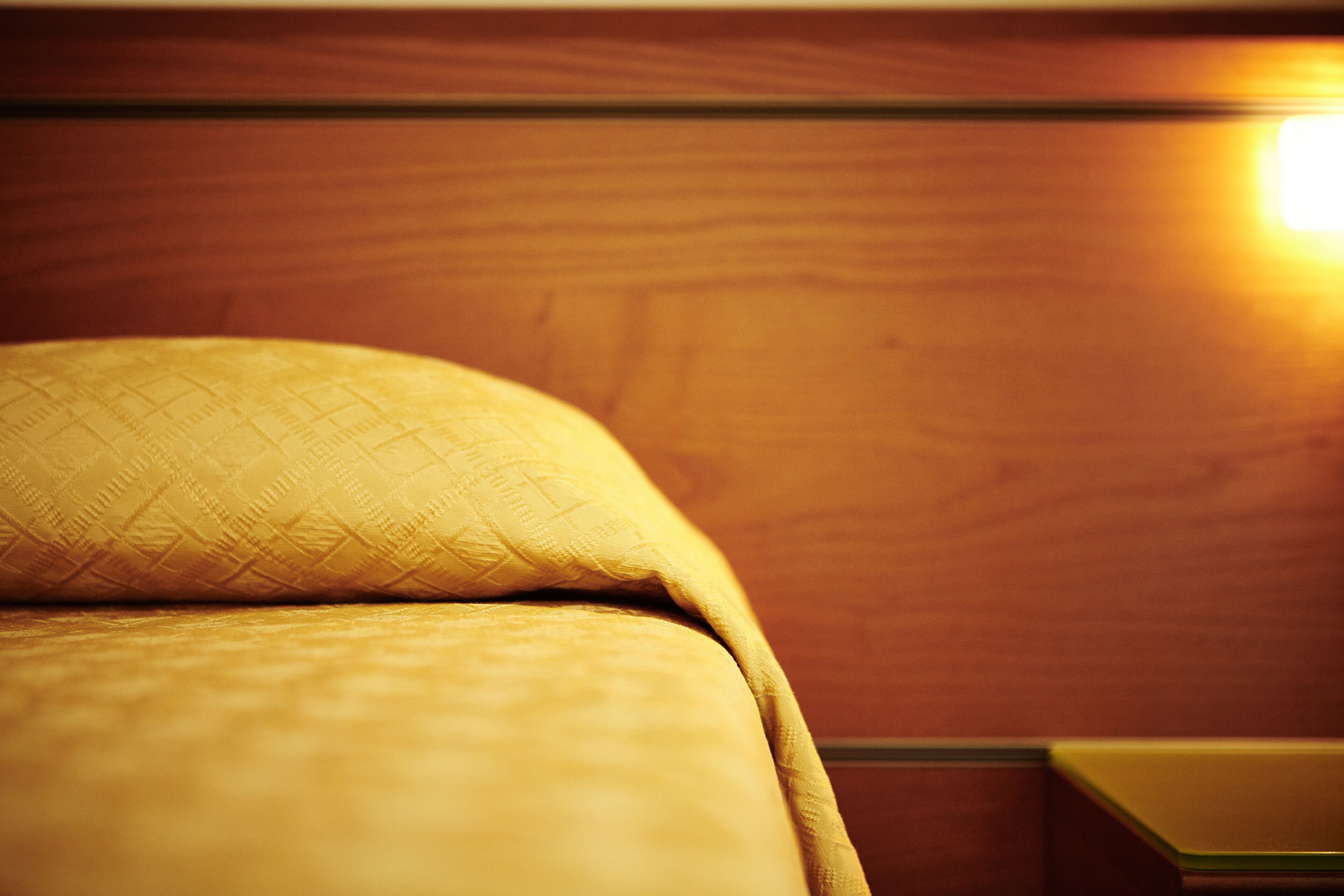 Ein Bett mit einer gewebten Decke und einem Holzkopfteil.