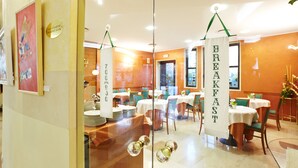 A breakfast area with tables and chairs, a sign indicating the breakfast room, and a glass partition with decorative elements. - Primhotel (Oderzo)