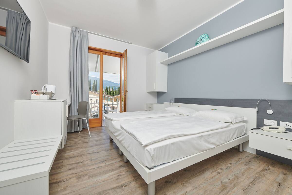 A modern bedroom with a large bed, bedside tables, a desk, and a chair.