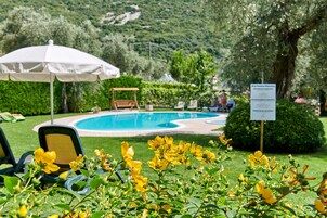 A pool area with lounge chairs, an umbrella, and a signboard.