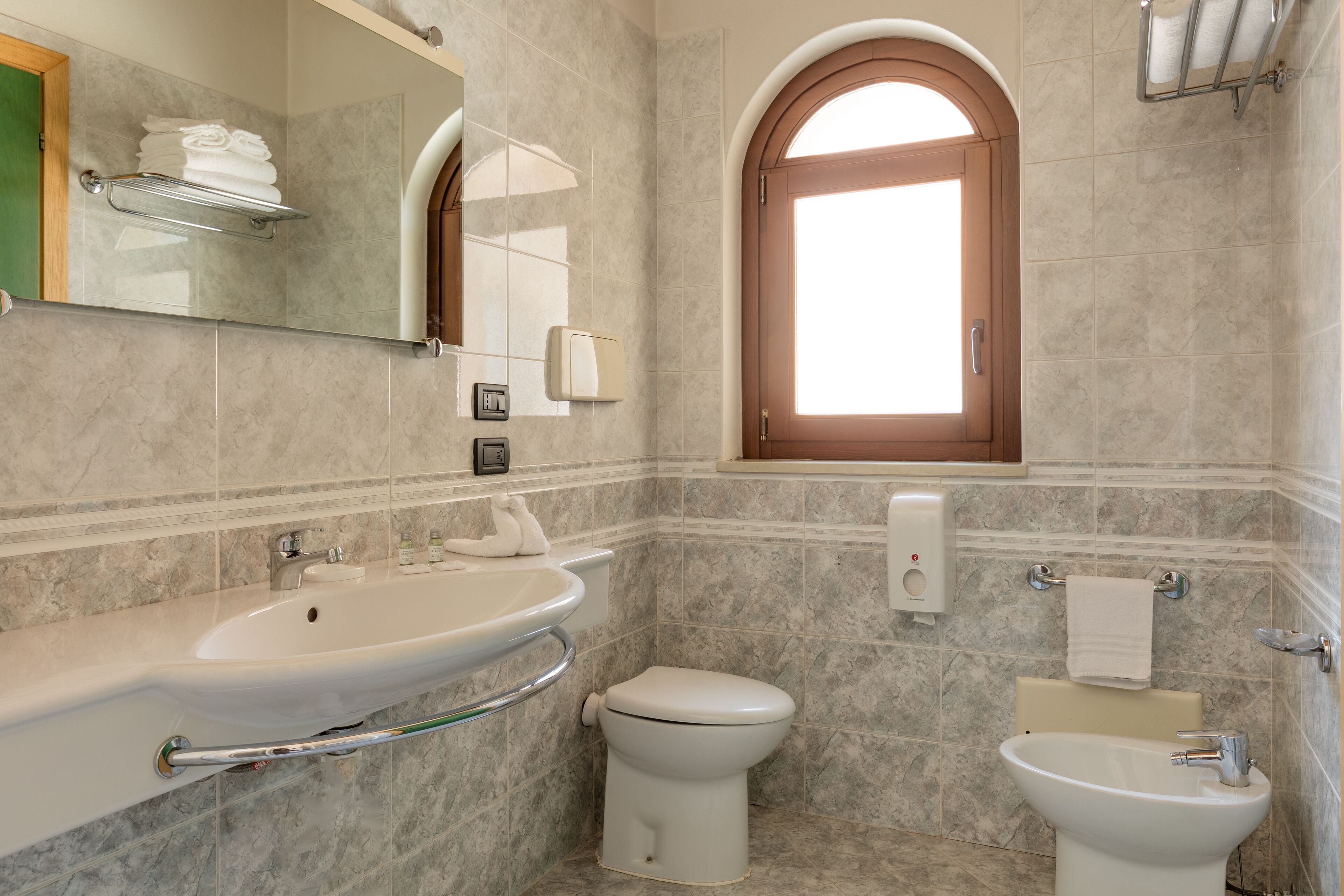 Un baño con lavamanos, inodoro, bidé y ventana.