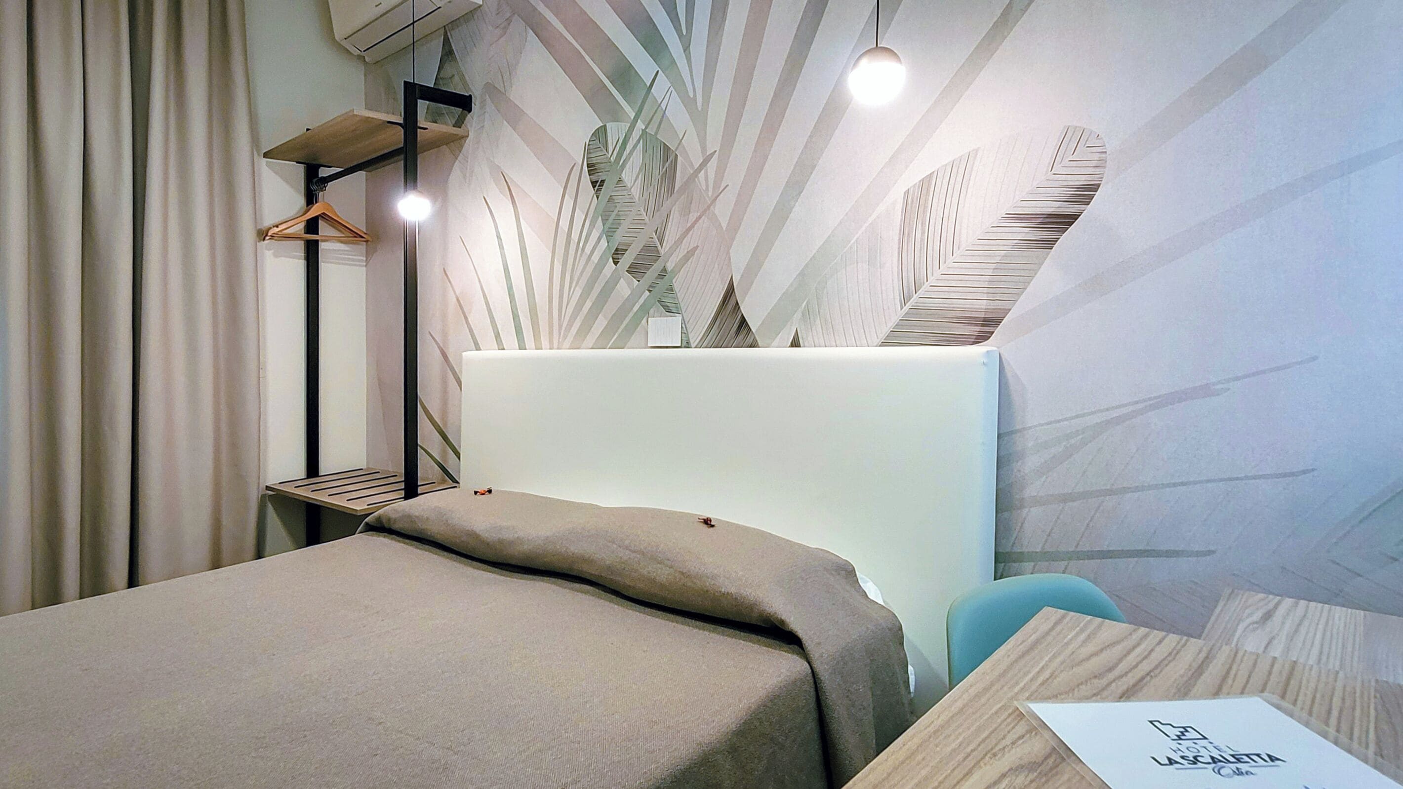 Una habitación de hotel moderna con una cama, un escritorio y una lámpara colgante.
