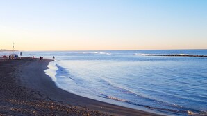 A beach with a clear sky, calm sea, and a few people walking. - Hotel La Scaletta (Rome)