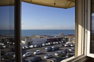 Un parcheggio con diverse auto e vista sul mare e sugli edifici sullo sfondo.
