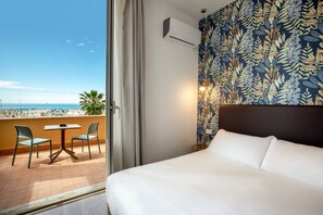 A hotel room with a bed, a small table with chairs, a view of the beach, and a patterned wall. - Hotel La Scaletta (Rome)