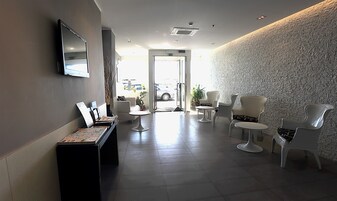 Un área de recepción con mostrador, zona de asientos y televisor instalado en la pared.
