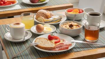 Une table dressée pour le petit-déjeuner, avec des croissants, des œufs, des tomates et une tasse de thé.