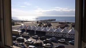A view of a parking lot with several cars and tents, a pier extending into the water, and a clear sky. - Hotel La Scaletta (Rome)