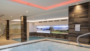 Ein Hallenbad mit Steinwand und Wandgemälde einer verschneiten Landschaft.