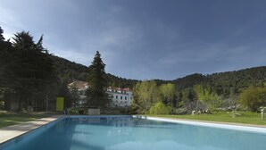 A rectangular swimming pool with clear blue water, surrounded by a grassy area and trees.