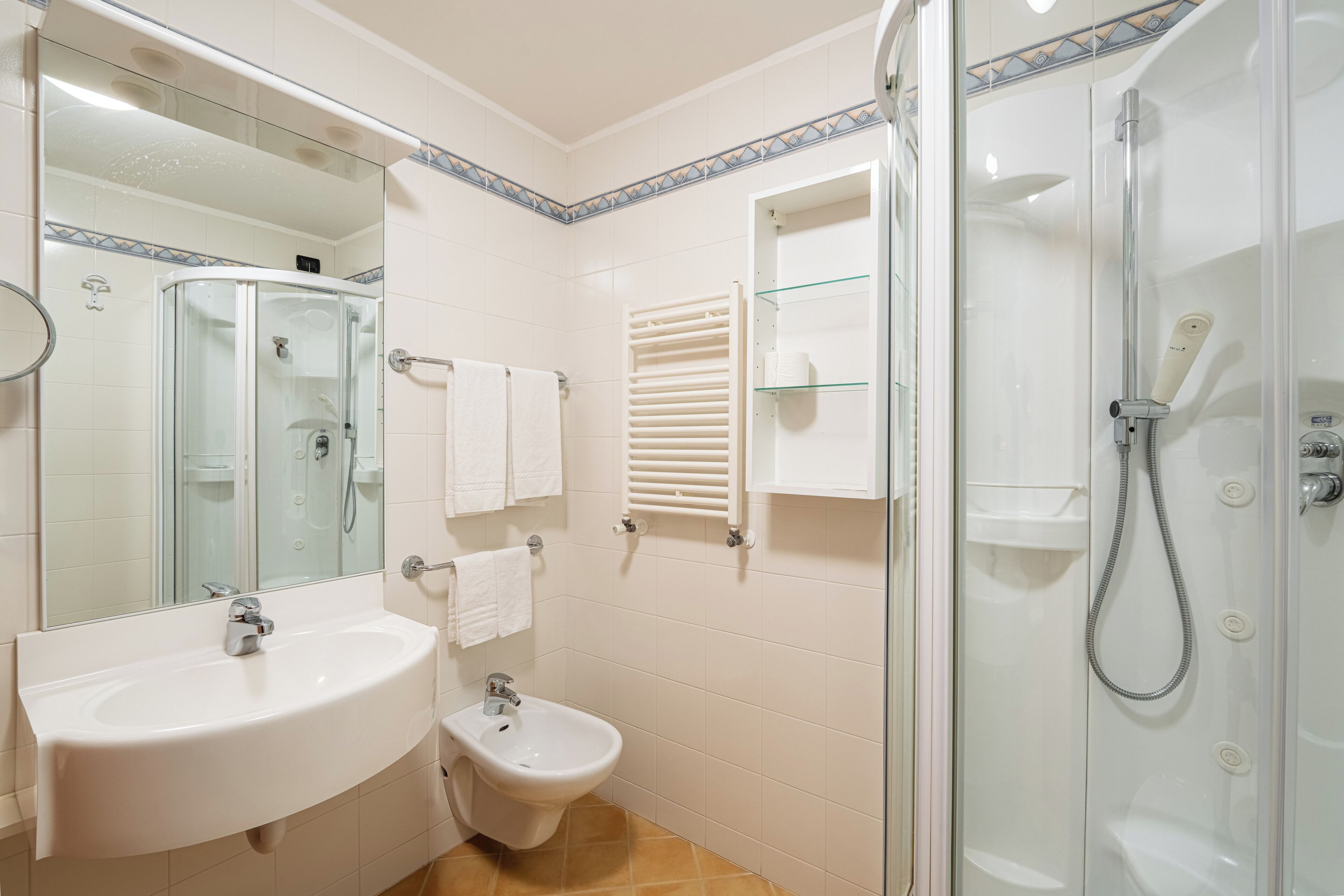 Ein Badezimmer mit einer Duschkabine, einem Waschbecken, einem Bidet und einem Spiegel.