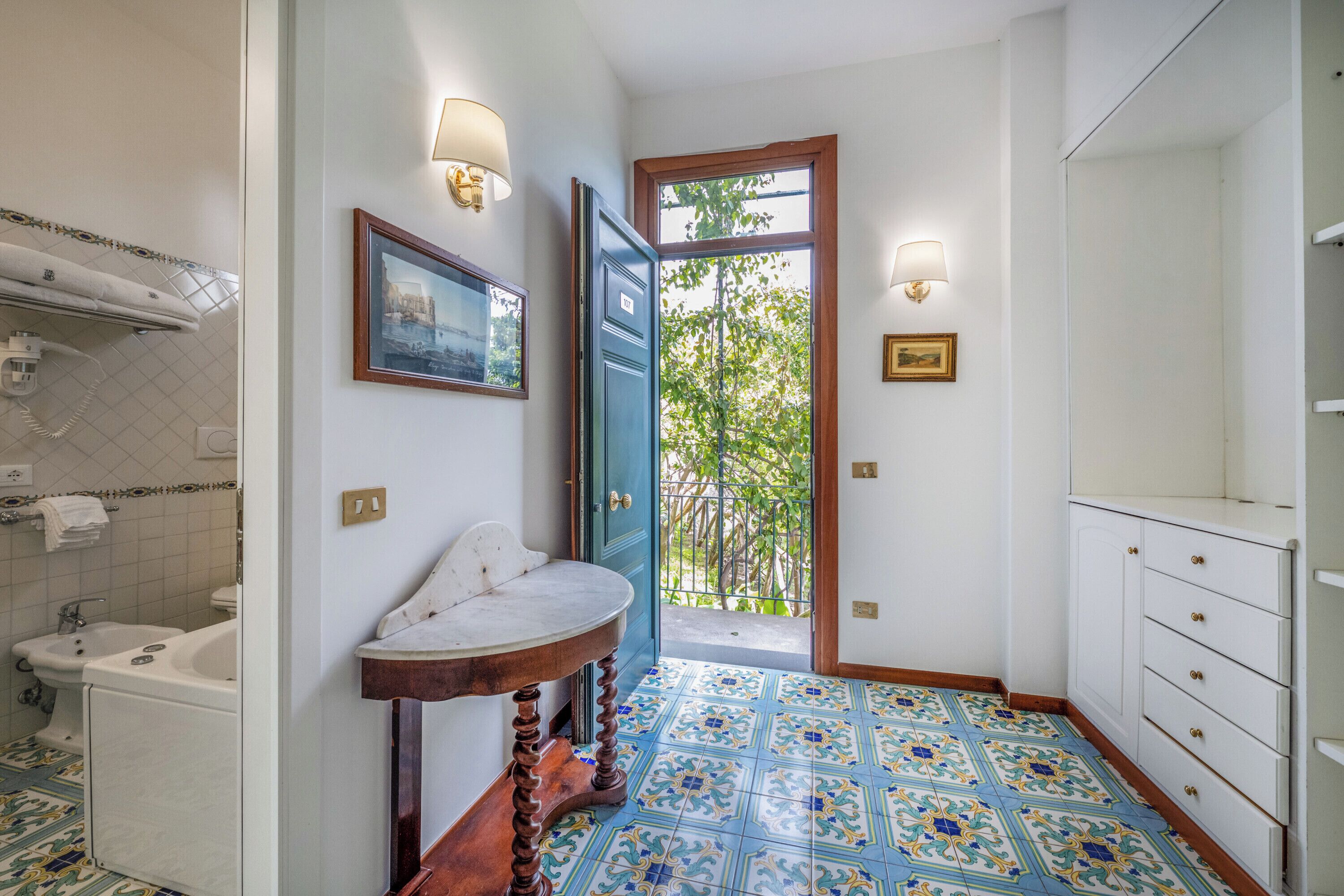 Une salle de bain avec un lavabo, un miroir et une porte donnant sur un balcon.